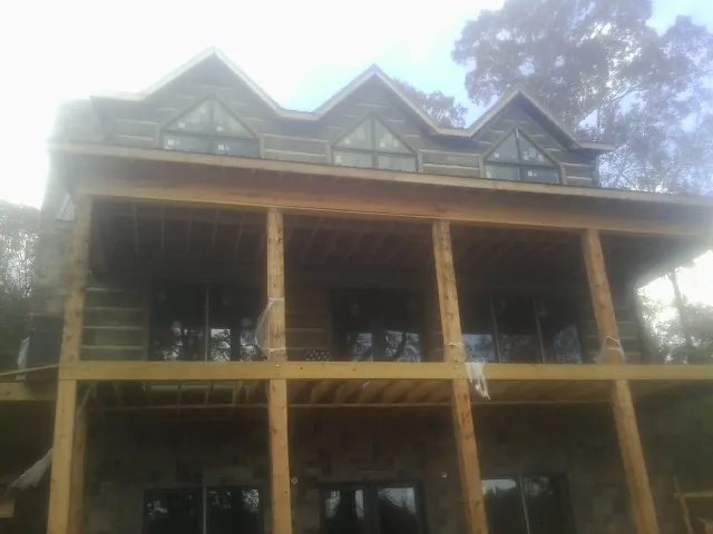 Dormers and porch framing on a large log home under construction — Roof Coating work by our crew in Ixonia