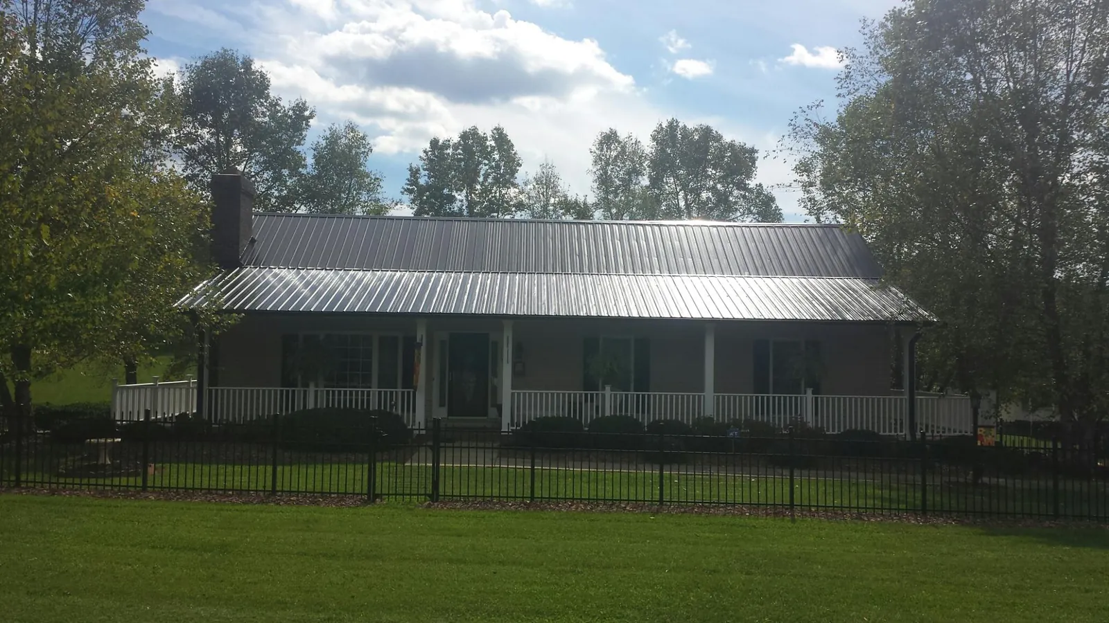 Gray metal roof on a brick ranch with a full width front porch — Gutter Guard Installation work by our crew in Ixonia