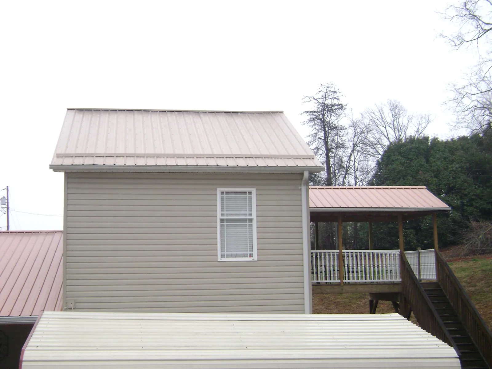 Tan metal roofs on a two story addition and attached porch, from a Roof Replacement job in Ixonia